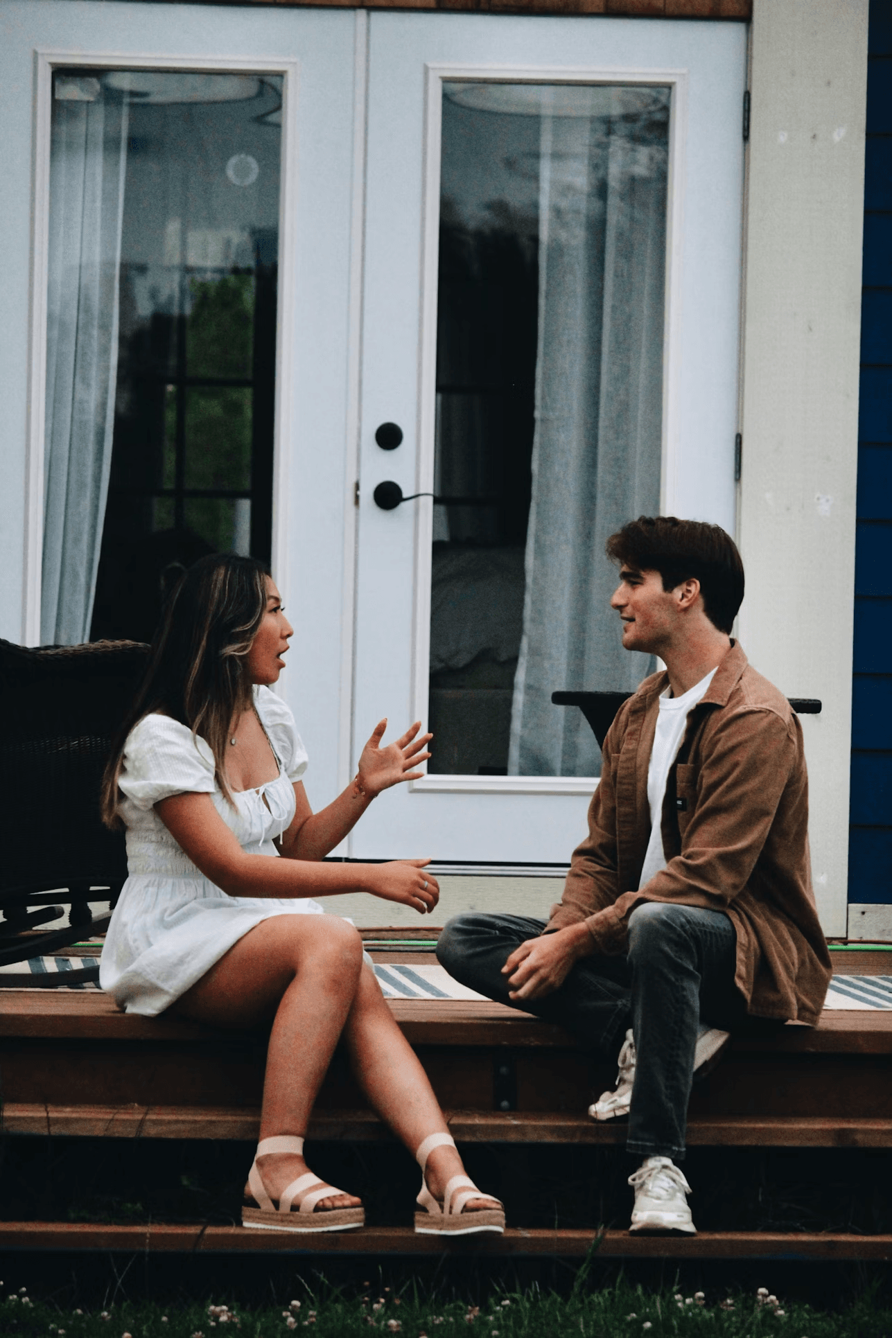 A man and woman sitting and talking on a porch