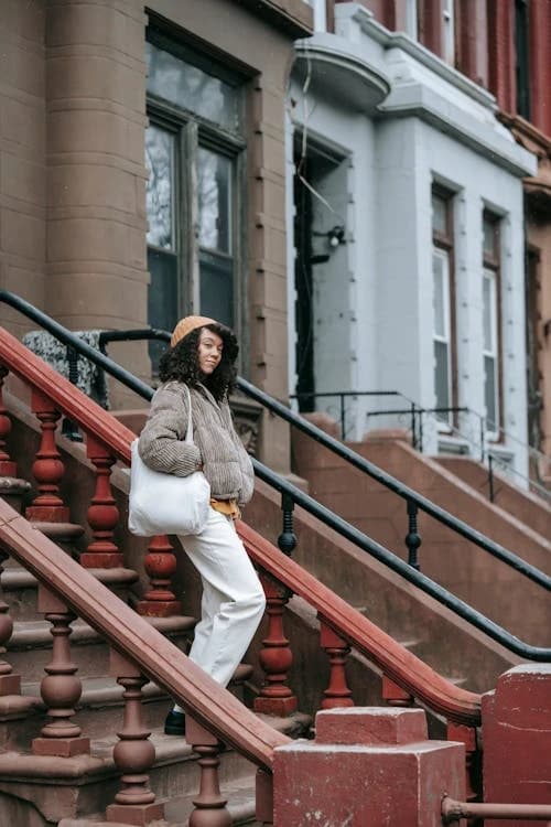 A woman with a tote bag on a New York brownstone stoop