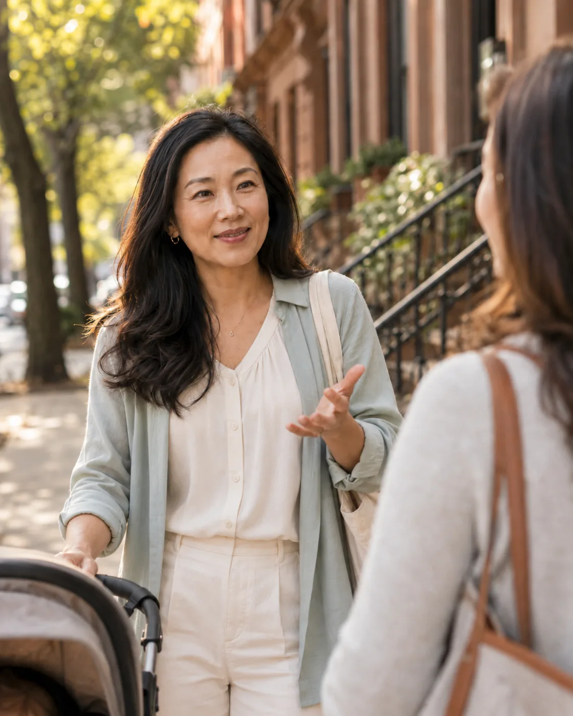 Two neighbors talking outside on a brownstone-lined street